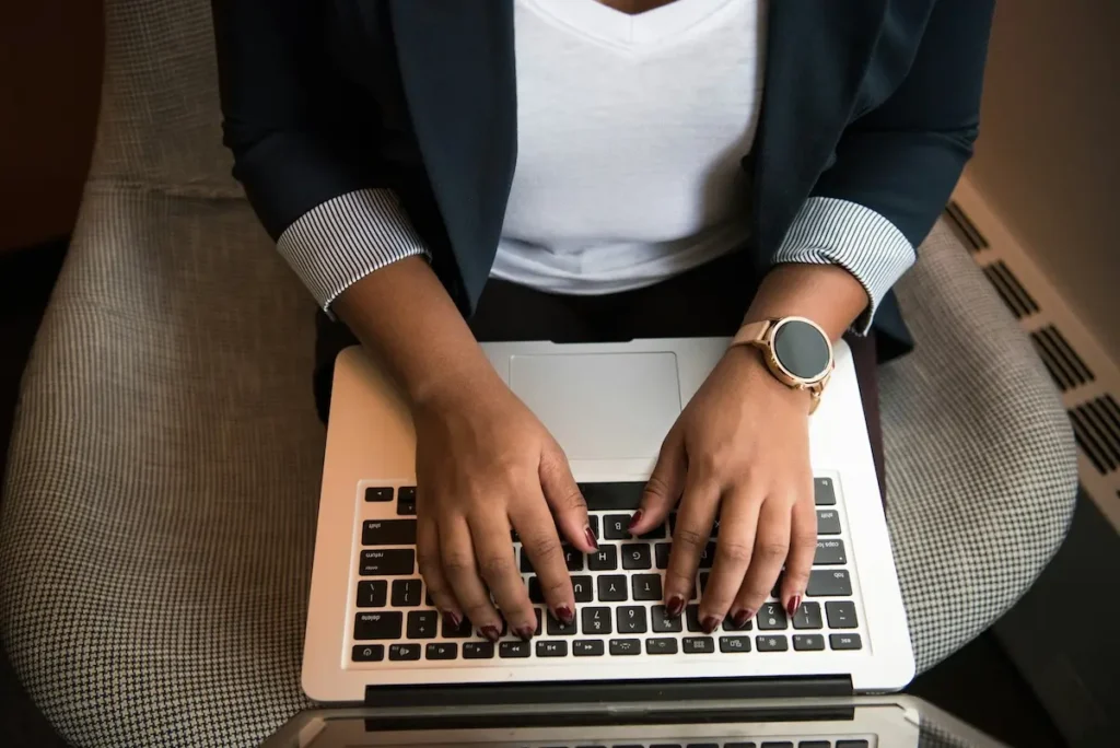 Closeup of a woman's hands typing on a laptop